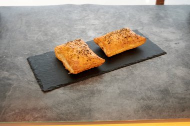 Siyah tabakta iki hamur işi. Biri solda ve diğeri sağda.