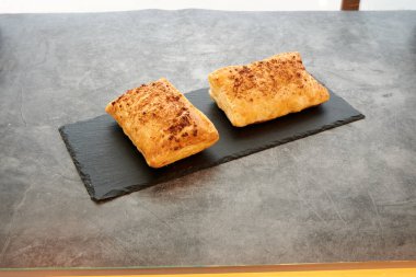 Siyah tabakta iki hamur işi. Biri solda ve diğeri sağda.