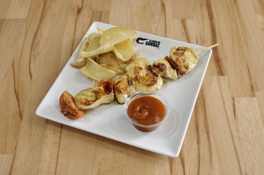 Soslu bir tabak yemek ve bir parça et. Sos kırmızı, et de tavuk.