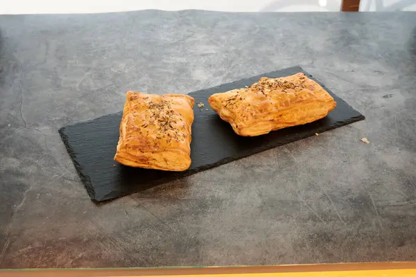 Siyah tabakta iki hamur işi. Biri solda ve diğeri sağda.