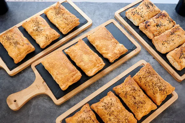 Altında tahta bir tahta olan bir tepsi hamur işi. Tahtada altı tane pasta var.