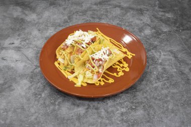 İki tabak peynirli ve marullu taco. Tabak gri bir tezgahın üzerinde.