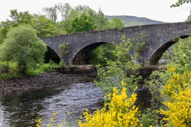 RIVER TÜMMEL, PERTHSHIRE, SCOTLAND, İngiltere, 25 MAYIS. 25 Mayıs 2024 'te İskoçya' nın Perthshire kentindeki Tummel Nehri üzerindeki eski taş köprü. Kimliği belirsiz iki kişi.