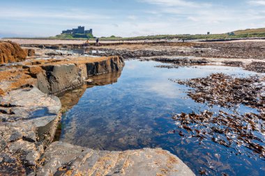 BAMBURGH, NORTHUMBERLAND, UK, AUGUST 15. Shoreline view to Bamburgh Castle in Bamburgh Northumberland on August 15, 2010. Unidentified people.