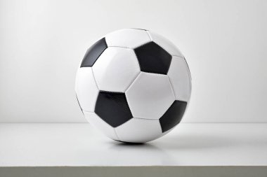 Masada ve açık gri arka planda izole edilmiş klasik siyah beyaz futbol topunun detaylı görüntüsü. Ön görünüm.