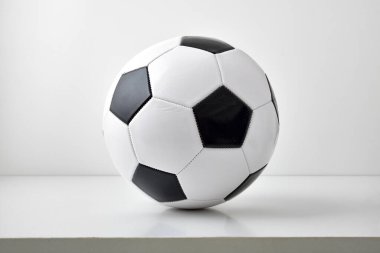 Gri masa ve açık arkaplanda izole edilmiş klasik siyah beyaz futbol topunun detaylı görüntüsü. Ön görünüm.