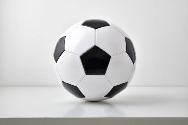 Klasik siyah-beyaz futbol topu merkezinin detaylı görüntüsü ve masa ve açık gri arka planda izole edilmiş hali. Ön görünüm.