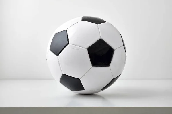 stock image Detail view of classic black and white leather soccer ball isolated on gray table and light background. Front view.