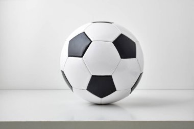 Masada ve açık gri arka planda izole edilmiş klasik siyah beyaz futbol topunun detaylı görüntüsü. Ön görünüm.