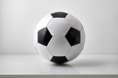 Masada ve açık gri arka planda izole edilmiş klasik siyah beyaz futbol topunun detaylı görüntüsü. Ön görünüm.