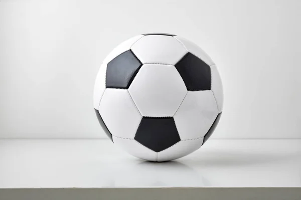 stock image Detail view of classic black and white leather soccer ball isolated on table and light gray background. Front view.