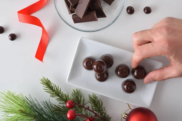 Beyaz masadaki bir tabaktan çikolatalı bonbon alırken daha fazla şeker ve Noel süsü aldım. Üst görünüm.