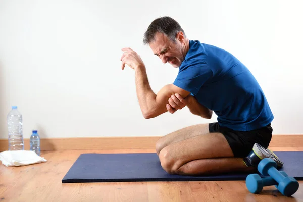 男は屋内で畳の上に座って痛みのトリップを不平を言うスポーツをしている サイドビュー — ストック写真