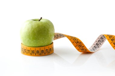 Apple on tape measure reflected on white base and white isolated background. Healthy life style. Front view.