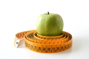 Rolled meter in a circle and apple inside reflected on white base and white isolated background. Healthy life style. Front view.