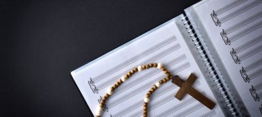 Müzik ve dini koro notalar ve ahşap haçla siyah masanın üstünde. Üst görünüm.