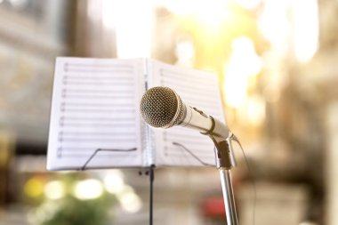 Kilisedeki mikrofon ve müzik standı olan dini şarkıların müzikal arka planına sahip kavram. Ön görünüm.