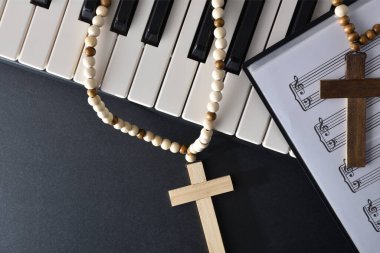 Piyano için dinsel müzik arka planında enstrüman ve siyah masanın üzerinde haçlar olan notalar. Üst görünüm.