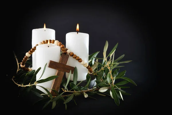 Easter religious background with three burning candles christian cross and olive branches around. Front view.