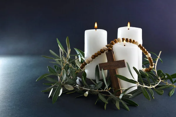 Easter religious background with three burning candles christian cross and olive branches around. Front view.