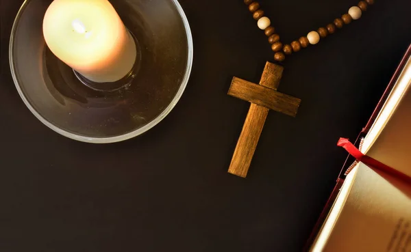 キリスト教の十字架 開いている聖書 ガラス板の上に灯されたキャンドルで祈るために宗教的な要素を持つ黒いベッドサイドテーブル トップ表示 — ストック写真