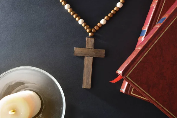 黑色床头柜 有宗教元素 用基督教十字架圣经和玻璃器皿上点燃的蜡烛祈祷 顶部视图 — 图库照片