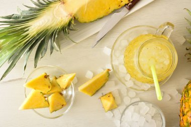 Taze hazırlanmış ananaslı meşrubat, ahşap mutfak tezgahında bol buzlu meyve ve etrafında buz olan bir kase. Üst Manzara. Yatay bileşim.