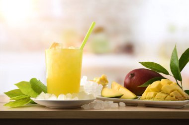 Ahşap mutfak tezgahında bol buzlu mango ve etrafında buz olan bir kase. Ön manzara. Yatay bileşim.