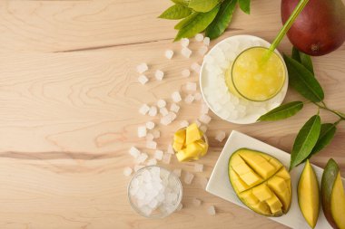 Ahşap mutfak tezgahında bol buzlu mango içeceği ve etrafı buzla kaplı bir kase. Üst Manzara. Yatay bileşim.