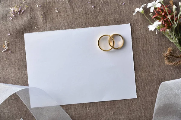 茶色の布と白いリボンや花の細部に切り取られた紙のリングで金のリングと結婚式の発表の背景 トップ表示 — ストック写真