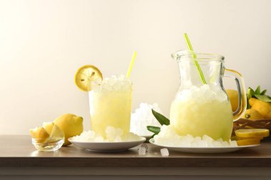 Sürahide buzlu limonata ve ahşap mutfak tezgahında cam meyveli ve izole arka planda ezilmiş buz. Ön manzara. Yatay bileşim.