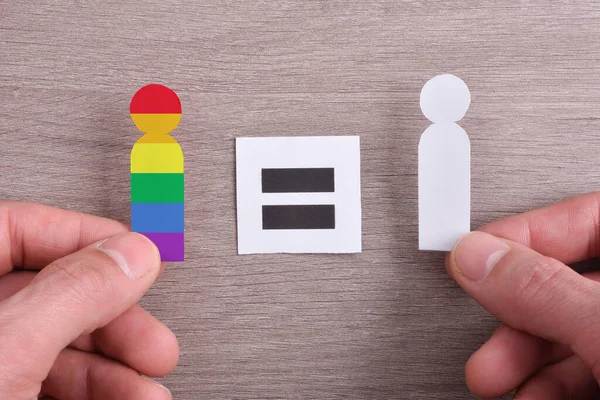 紙の人々の切り抜きとの性的多様性とジェンダー多様性の比較や木製のテーブルの上に等しいシンボルを持つ手保持記号 トップ表示 — ストック写真