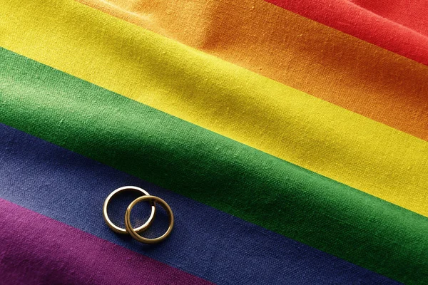 虹色のテクスチャフラグ上の金のリングとLbtのコレクティブの人々の間の結婚式の概念的な詳細 上からの眺め — ストック写真