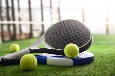 Sahadaki suni çim zemininde Padel raketler ve toplar. Ön görünüm.