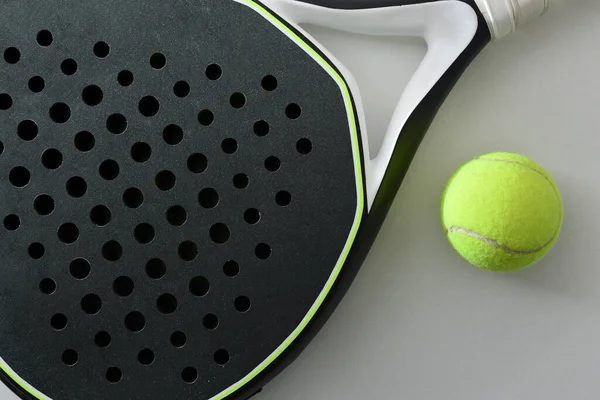 stock image Detail of black and white paddle tennis racket and ball on a white table. Top view.