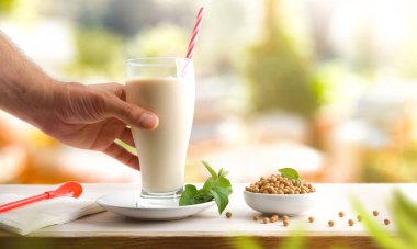 Cam bardak şişesi ve soya içeceği ve beyaz arka planda izole edilmiş ahşap masa üzerinde soya fasulyesi dolu bir kâse. Ön görünüm.