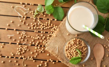 Soya içeceği ve soya fasulyesi dolu bir bardak ahşap masanın üzerinde. Üst görünüm.