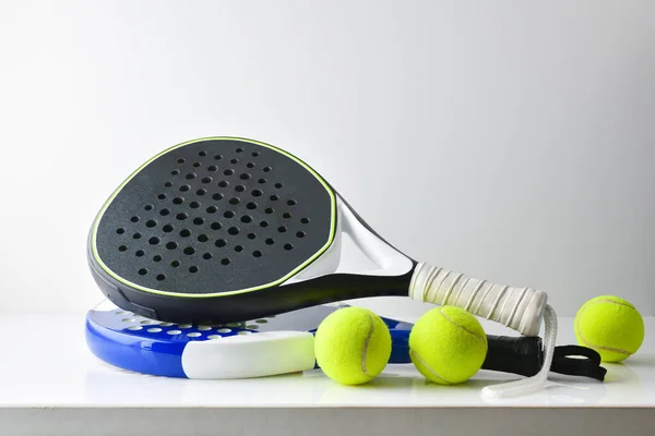 stock image two blue and black paddle rackets on white table with balls and white isolated background. Front view.