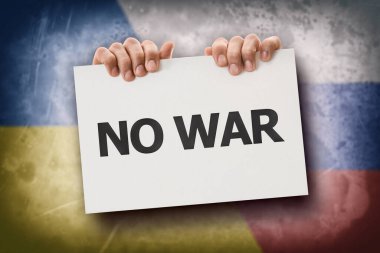 Rusya ile Ukrayna arasındaki savaşa karşı protesto kavramı. Elleri yazılı ve bayraklı bir tabela tutuyor..