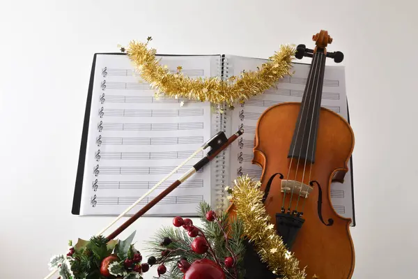Christmas religious violin music concept with violin with christmas decoration and sheet music  with white isolated background. Front view.
