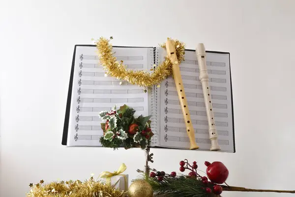 Recorders on music stand with sheet music and Christmas decoration with a religious temple background. Front view.