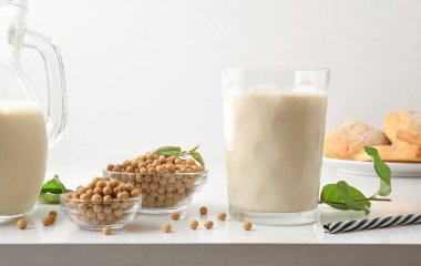 Süt ve soya ekmeği ile kahvaltı, tahıl dolu kaseler ve yapraklarla birlikte. Ön görünüm.