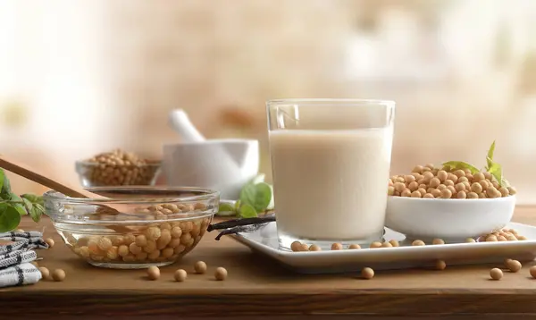 stock image Fresh soy drink made with seeds and kitchen utensils on a wooden bench in a kitchen. Front view.