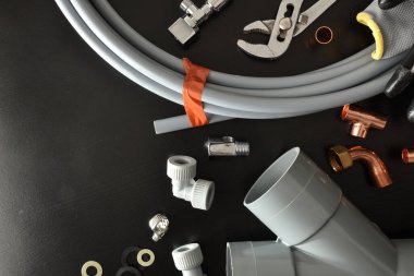 Bir grup tesisat malzemesi ve aletler siyah tezgahta. Üst Manzara. Yatay bileşim.