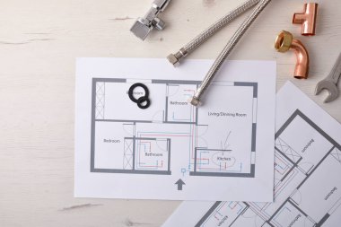 Ofis masası ve çeşitli malzeme unsurları üzerinde şeması ve planları olan evlerdeki su tesisleri ve reformlarında mühendislik ve geliştirme. Üst Manzara. Yatay bileşim.