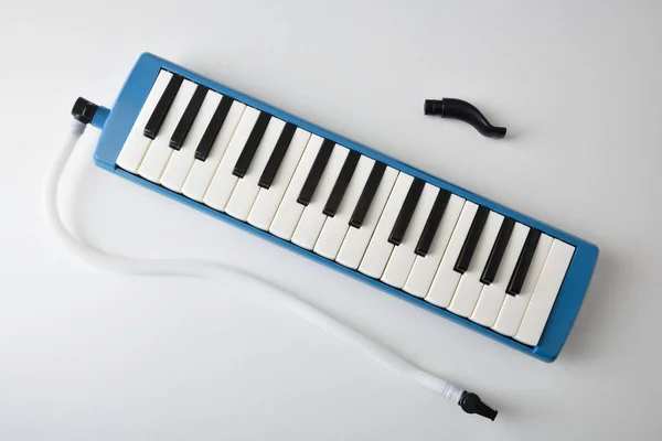 Presentation of melodica prepared to play with the tube and mouthpiece isolated on a white table. Top view.