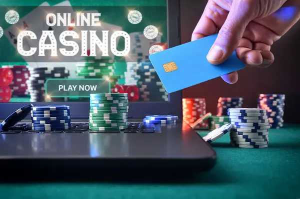 Casino game player accessing a payment card to make virtual bets using a laptop. Front view.