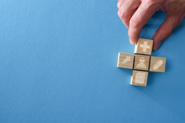 Tıbbi sağlık konsepti, ahşap küplere tıbbi semboller koyup mavi masaya haç koyuyor. Üst görünüm.