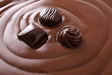 Çikolata kremasına batırılmış üç farklı siyah çikolata şekeri. Yüksek görünüm.