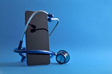 Cep telefonunun etrafında steteskopla izole edilmiş mavi arka planda internet sağlık hizmeti. Ön görünüm.